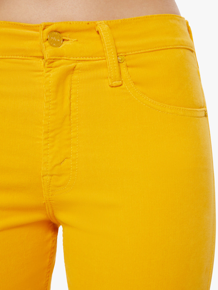 Waist close up view of a woman mid-rise straight leg with an ankle-length inseam and a clean hem in a yellow hue corduroy fabric.