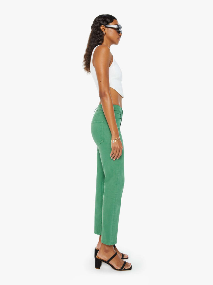 Side view of a woman in green straight-leg pants with tonal hardware and styled in a white tank top.