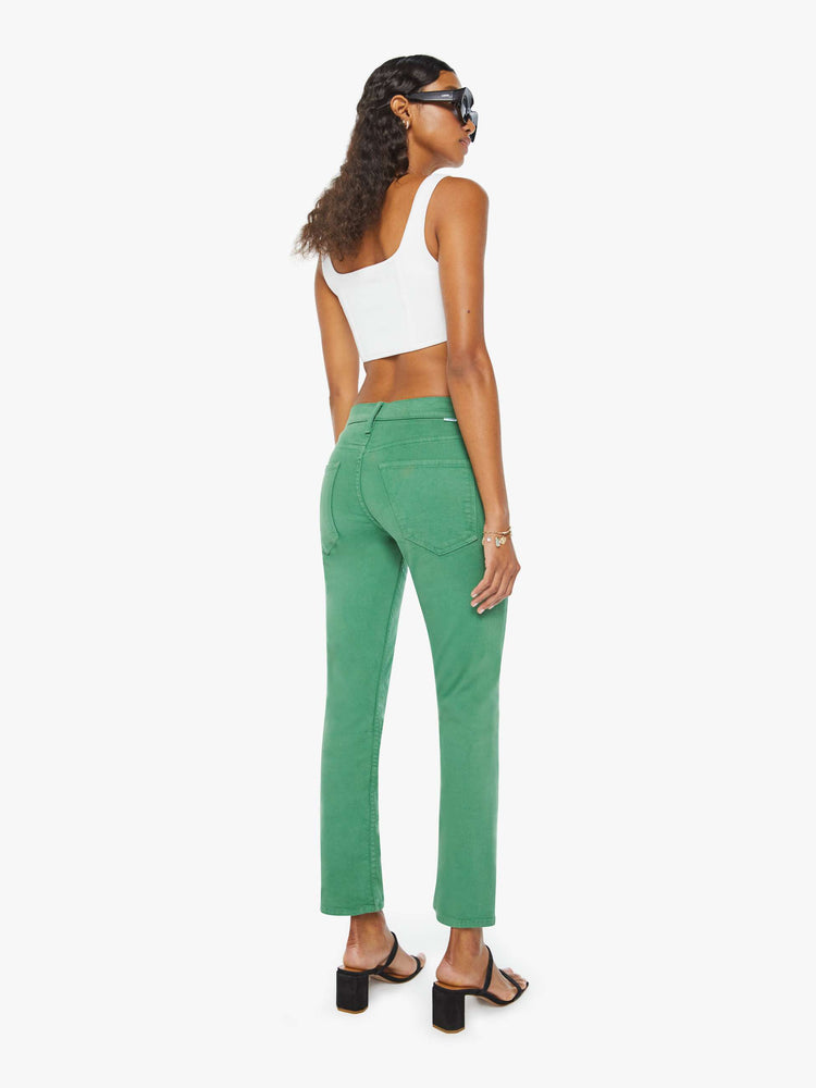 Backview of a woman in green straight-leg pants with tonal hardware and styled in a white tank top.