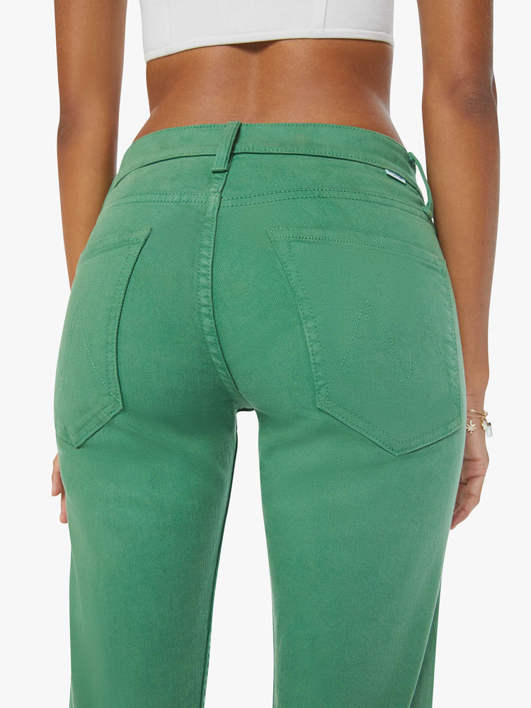 Swatch view of a woman in green straight-leg pants with tonal hardware and styled in a white tank top.