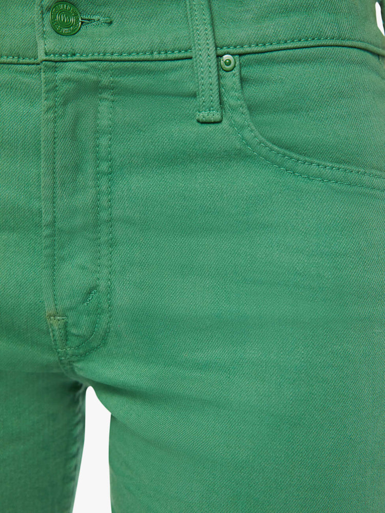 Detailed view of a woman in green straight-leg pants with tonal hardware.