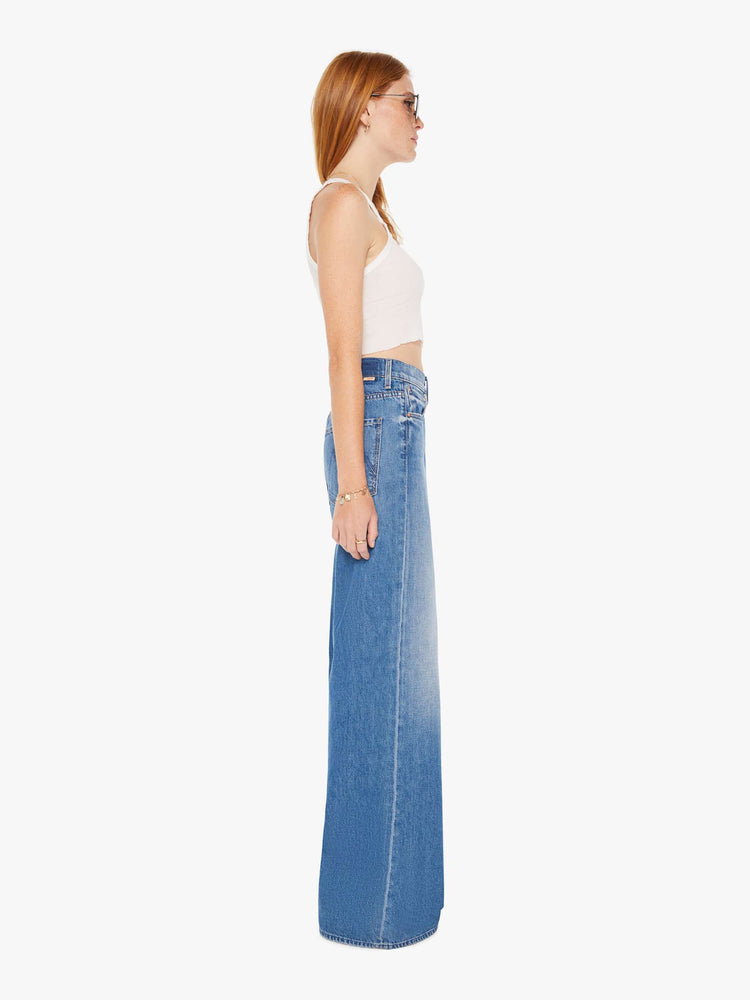 Side view of a womens medium blue wash jean featuring a slouchy mid rise, a wide leg, and clean hem.