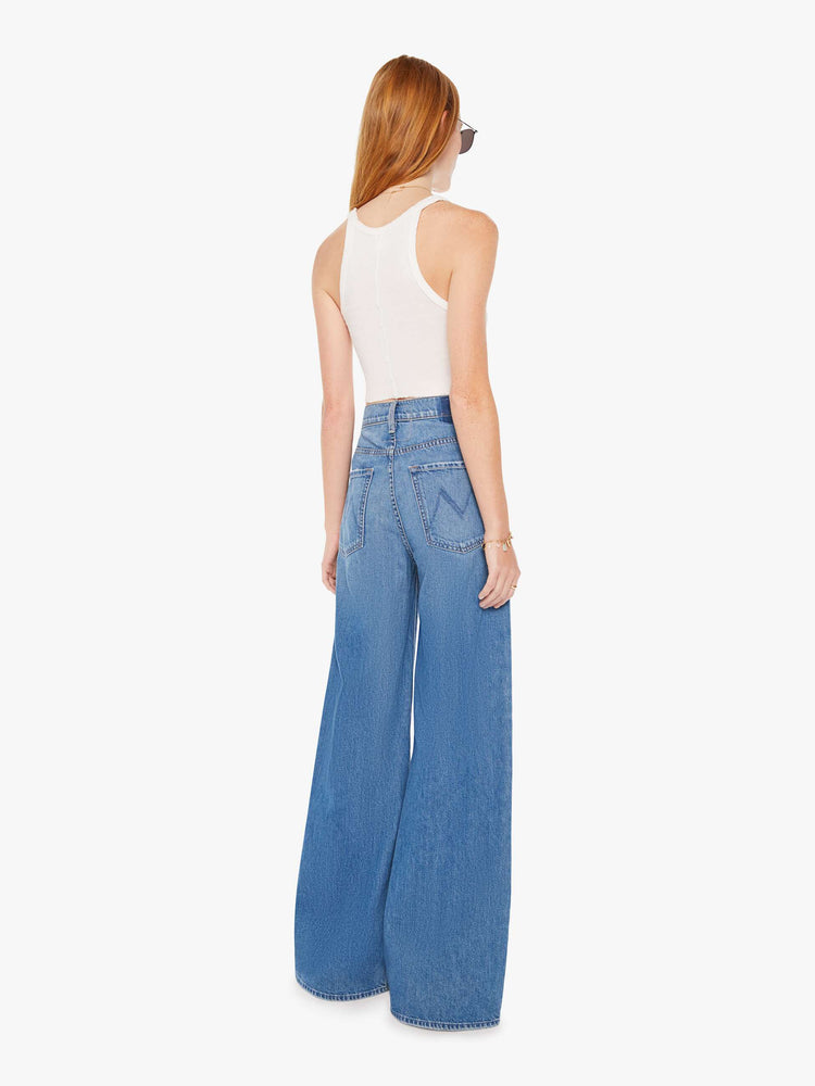 Back view of a womens medium blue wash jean featuring a slouchy mid rise, a wide leg, and clean hem.