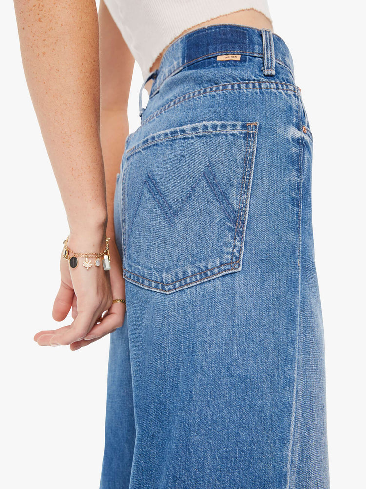 Side close up view of a womens medium blue wash jean featuring a slouchy mid rise.