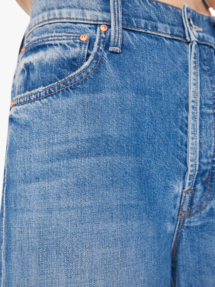 Side close up view of a womens medium blue wash jean.