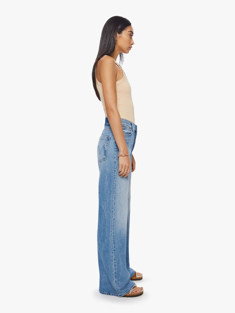 Side view of woman wide-leg jeans feature a button fly, low-set back pockets, mid-rise with a slouchy fit and a 32-inch inseam in a vintage blue.