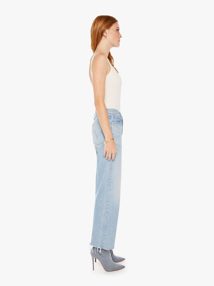 Side view of a womens light blue wash jean featuring a high rise, a straight leg, and frayed hem.