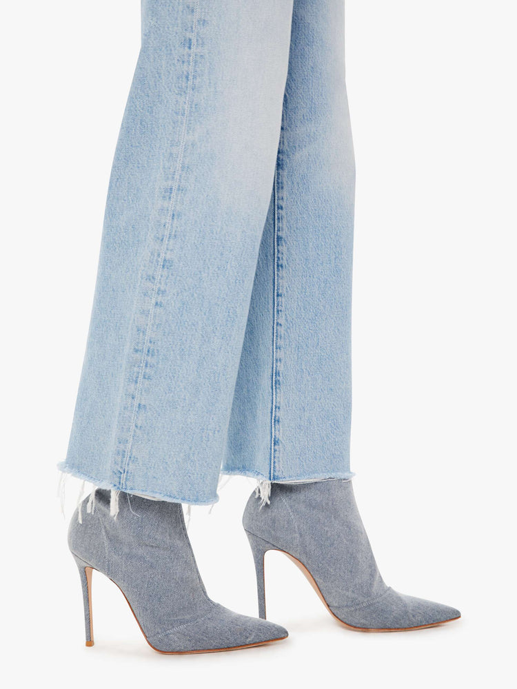 Side close up view of a womens light blue wash jean featuring a high rise, a straight leg, and frayed hem.