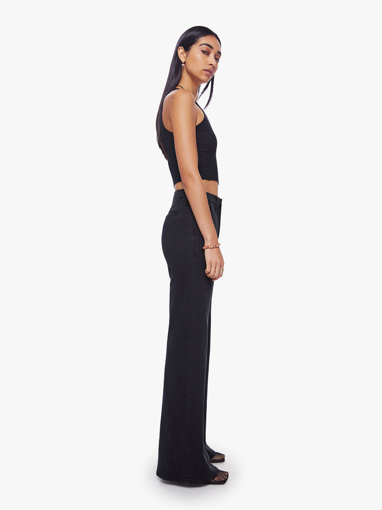 Side angle view of a woman high-waisted wide leg pant features back slit pockets, a 34-inch inseam and a clean hem in a solid black hue.