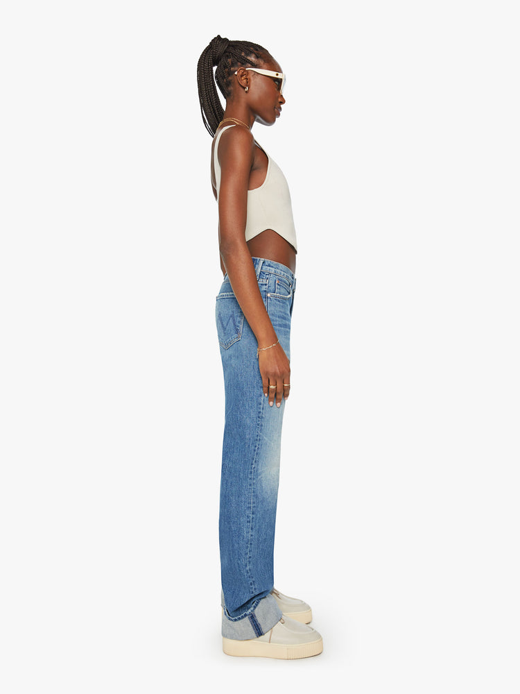 Side view of a woman straight-leg jean with a high rise and a 29-inch inseam with a thick folded hem in mid blue wash.