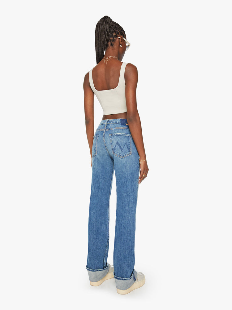 Back view of a woman straight-leg jean with a high rise and a 29-inch inseam with a thick folded hem in mid blue wash.
