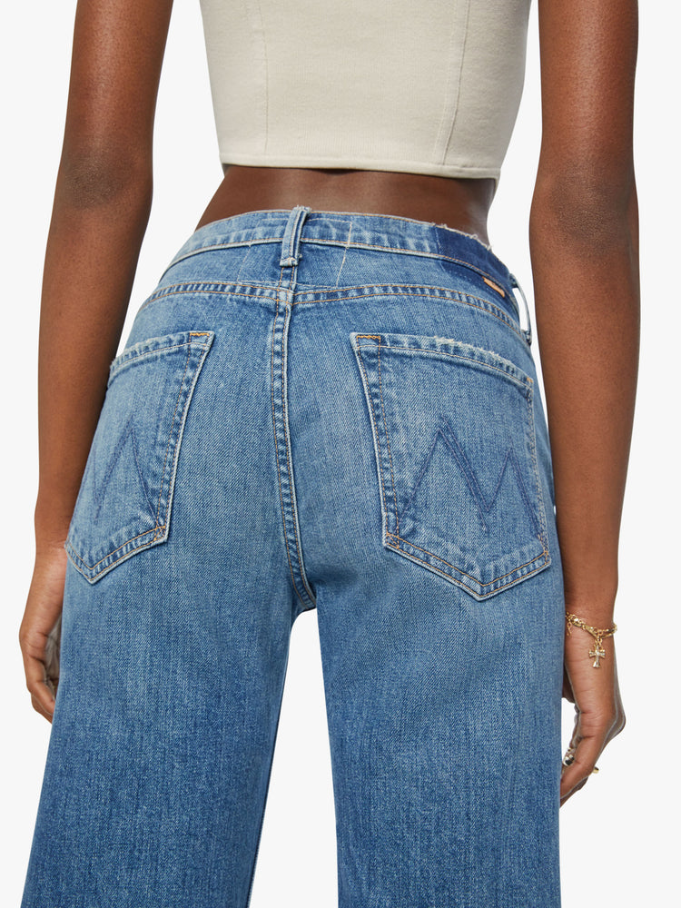 Close up waist view of a woman straight-leg jean with a high rise and a 29-inch inseam with a thick folded hem in mid blue wash.