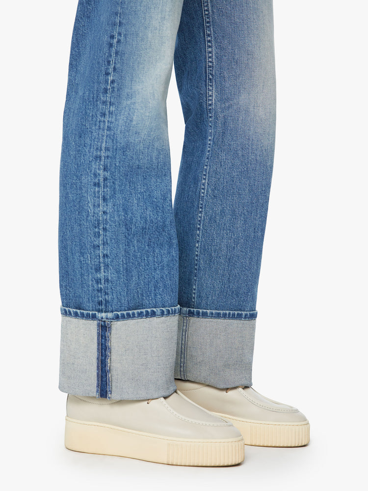 Hem view of a woman straight-leg jean with a high rise and a 29-inch inseam with a thick folded hem in mid blue wash.