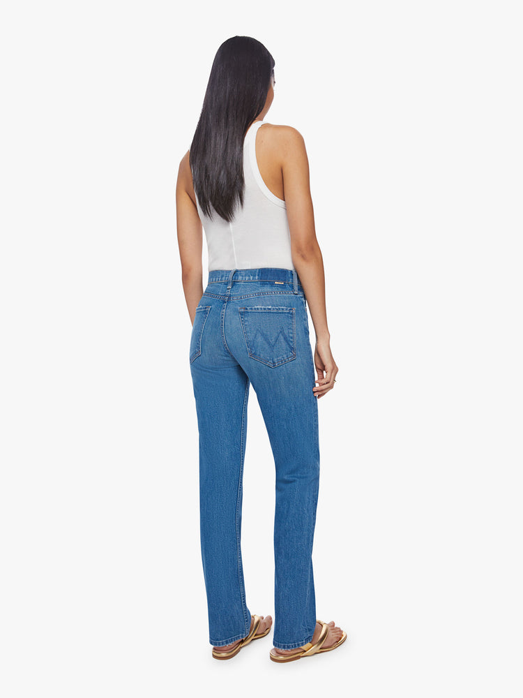 Back view of a woman high-rise jeans with a narrow straight leg and a 31-inch inseam with a clean hem in a mid-blue wash.