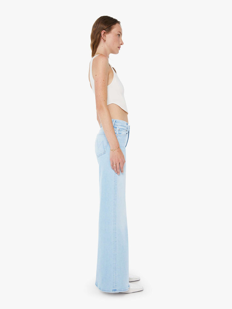 Side view of a woman in a wide-leg jeans with a mid rise, 32-inch inseam and a clean hem in a light blue wash.