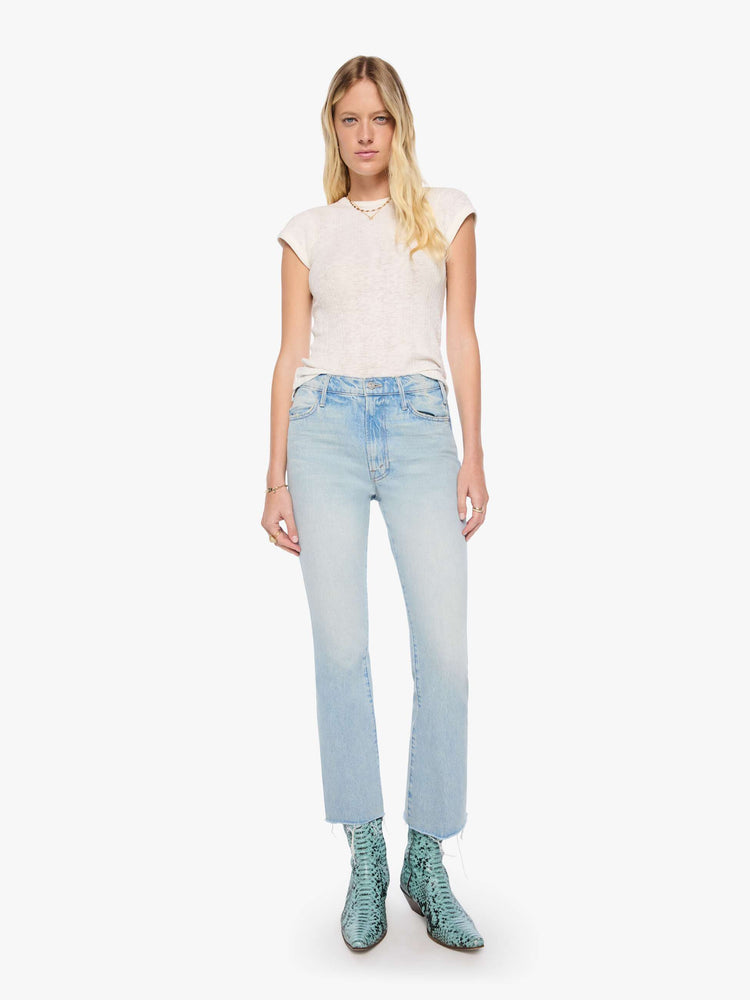Front view of a woman in a light blue  high-rise flare has a zip fly, 28.25-inch inseam and a frayed hem. 