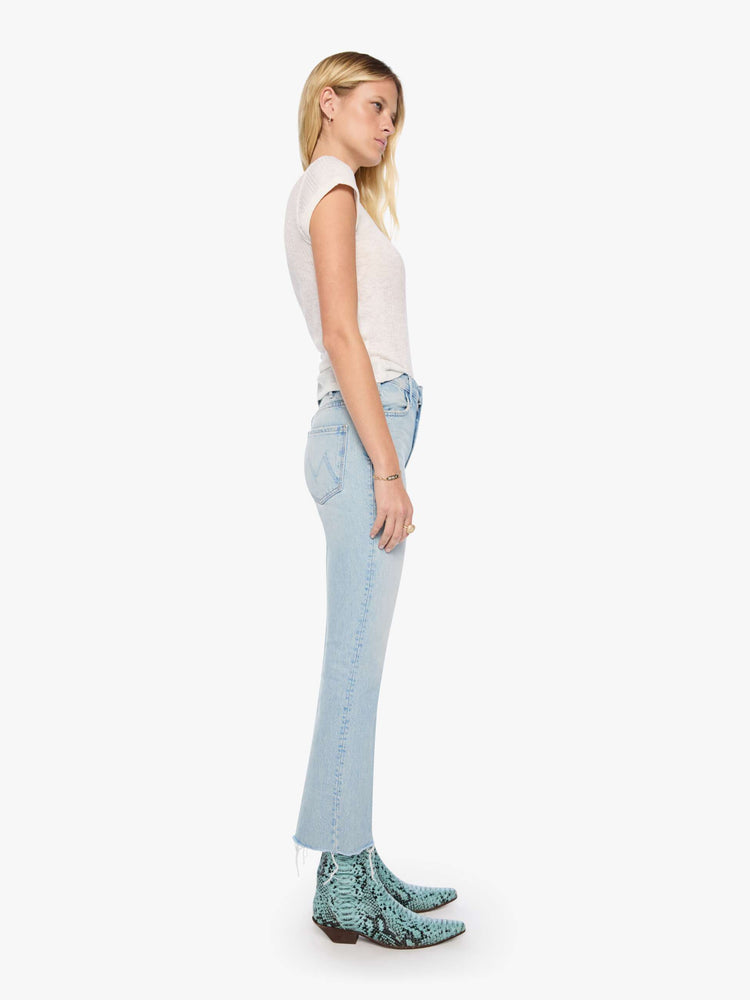 Side view of a woman in a light blue  high-rise flare has a zip fly, 28.25-inch inseam and a frayed hem. 