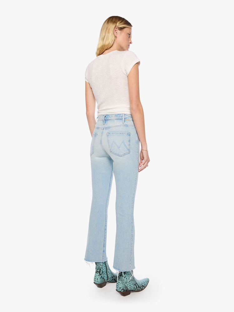 Back view of a woman in a light blue  high-rise flare has a zip fly, 28.25-inch inseam and a frayed hem. 