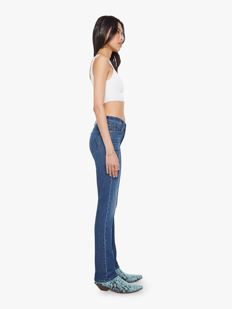 Side view of a woman in a dark mid-rise straight leg jean with a zip fly, long 31-inch inseam and a clean hem.