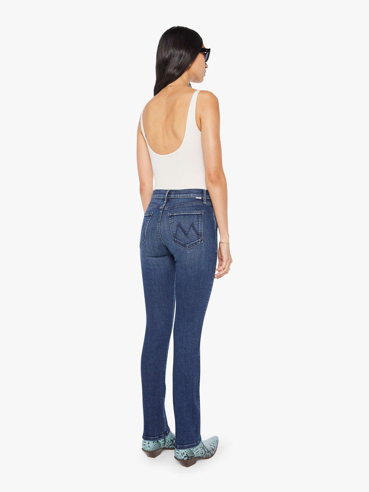 Back  view of a woman in a dark blue mid-rise straight leg with a zip fly, long 31-inch inseam and a clean hem.