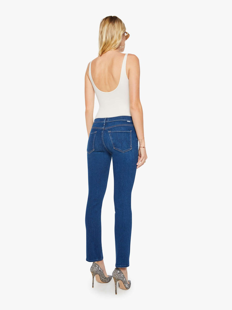 Back view of a woman in a dark blue  mid-rise straight-leg with a zip fly, long 31-inch inseam and a clean hem.