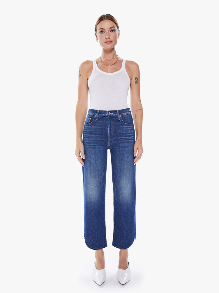Front view of a women in a high-waisted jean with a wide straight leg, zip fly and an ankle-length inseam with curved side seam in a blue hue.