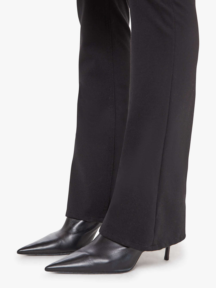 Hem view of a woman in a black high-rise flared trouser with a zip fly and a 34-inch inseam with a clean hem.