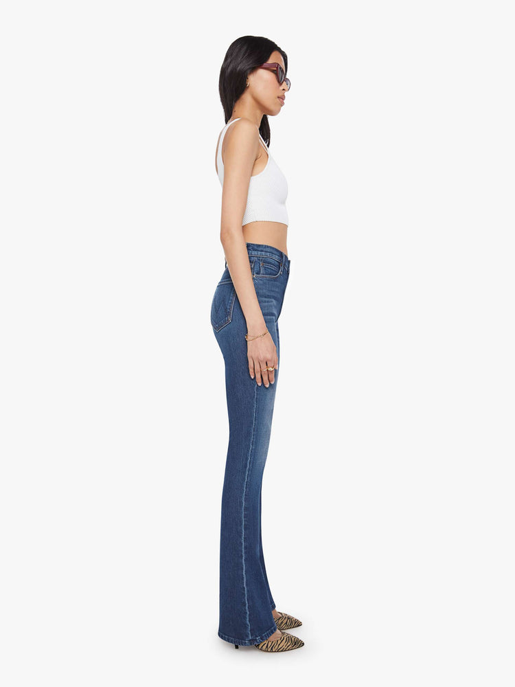 Side view of a woman in a skinny flare with a high rise, zip fly and a long 34-inch inseam with a clean hem.
