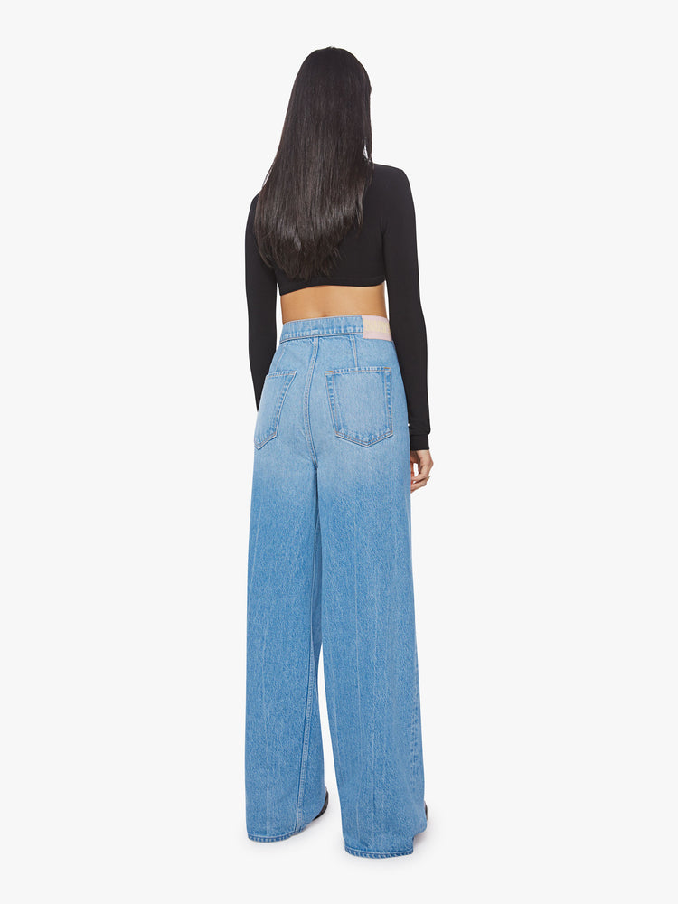 Back view of a woman wide leg jean with super high-rise jeans feature a loose, full leg, a wrapped waist that ties in the front and a long 32-inch inseam in a mid blue wash.