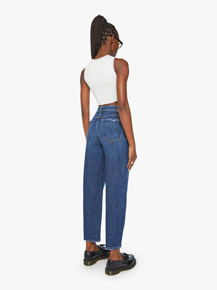 Back view of a woman super high-waisted jeans with a straight barrel leg and a cropped inseam with a clean hem in a dark blue wash.