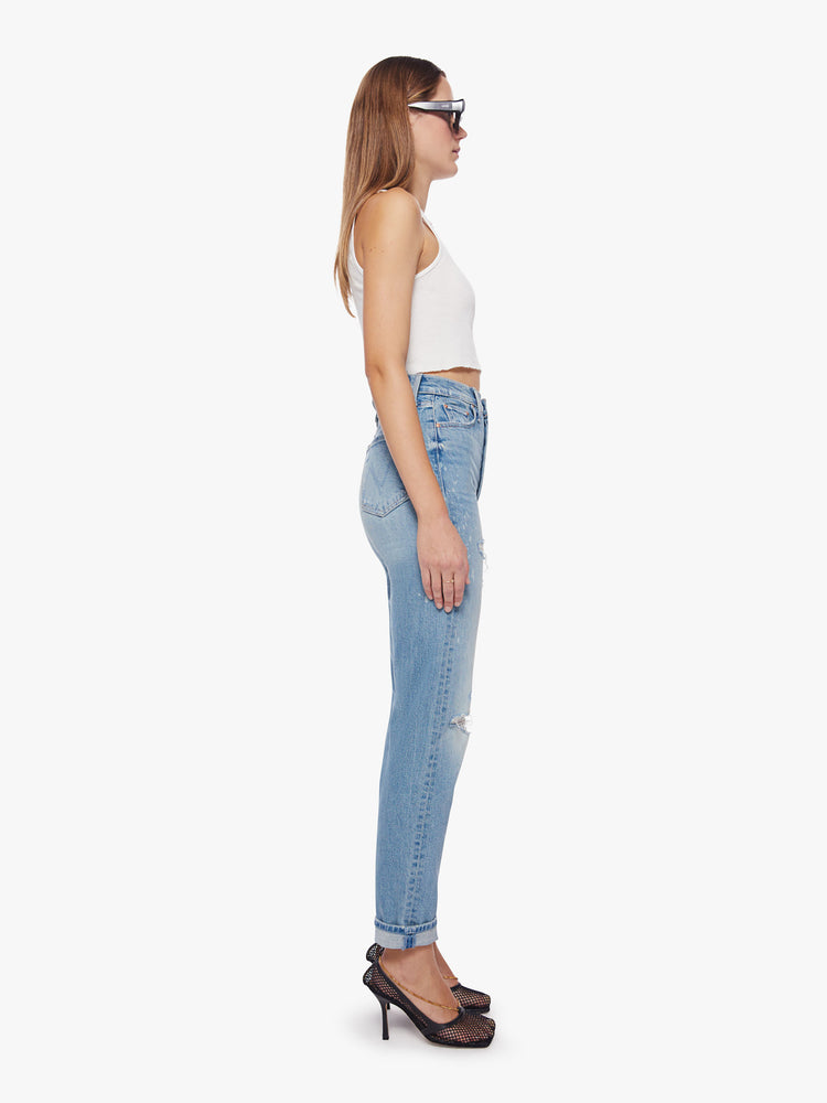 Side view of a woman ultra high-rise jeans with a straight, narrow leg and a cuffed 29-inch inseam in a light blue wash with bleach splatters.