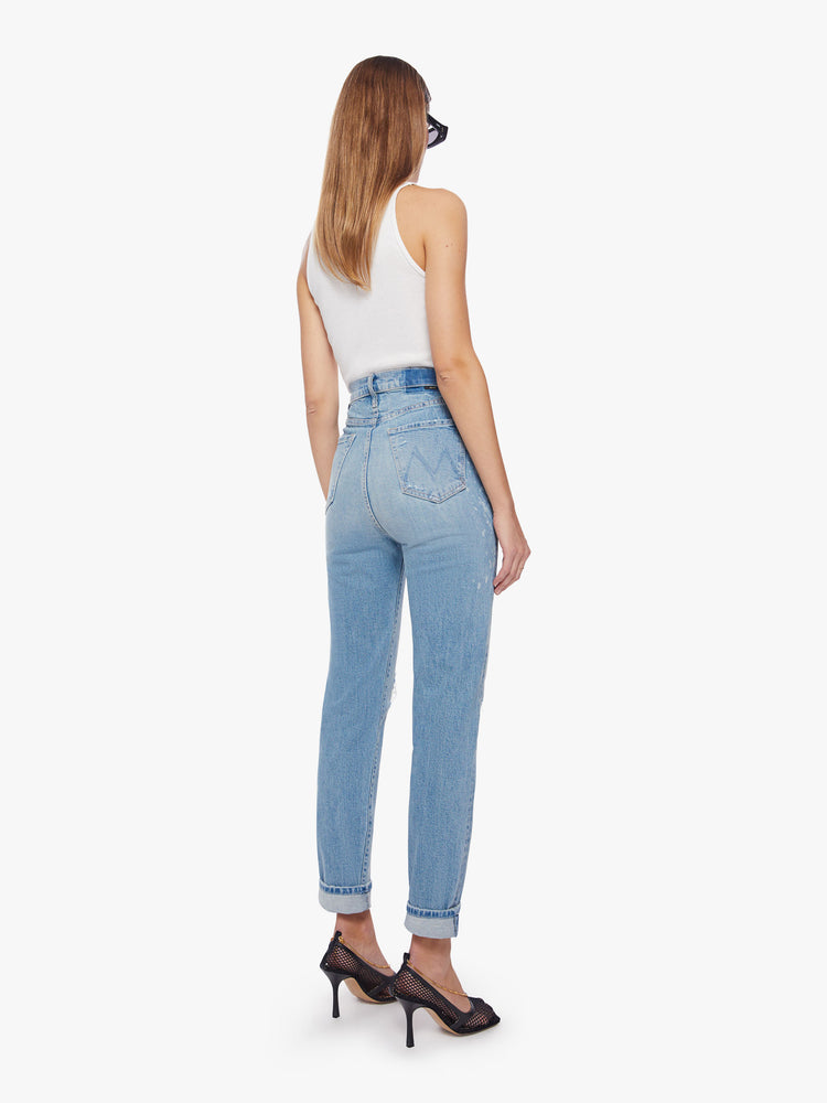 Back view of a woman ultra high-rise jeans with a straight, narrow leg and a cuffed 29-inch inseam in a light blue wash with bleach splatters.