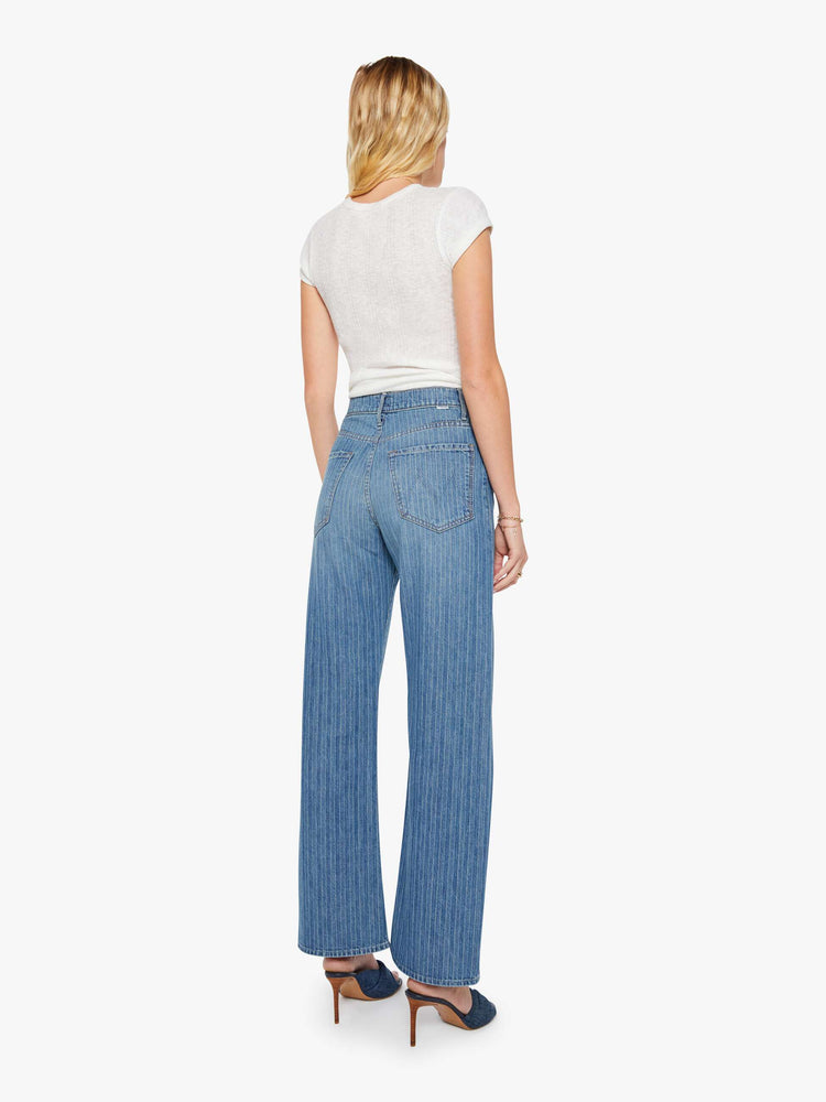 Back view of a woman in a mid-blue with Japanese pinstripes in white and fading at the knees wide-leg pant with a zip fly, high rise and a 32-inch inseam with a clean hem.