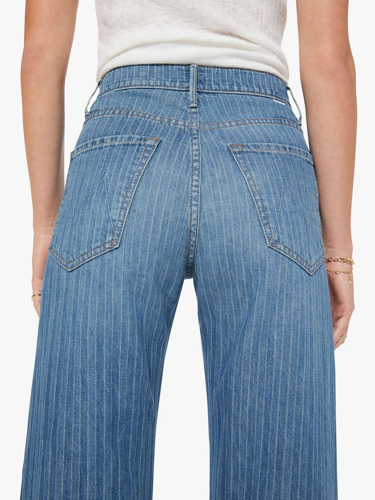 Close up view of a woman in a mid-blue with Japanese pinstripes in white and fading at the knees wide-leg pant with a zip fly, high rise and a 32-inch inseam with a clean hem.