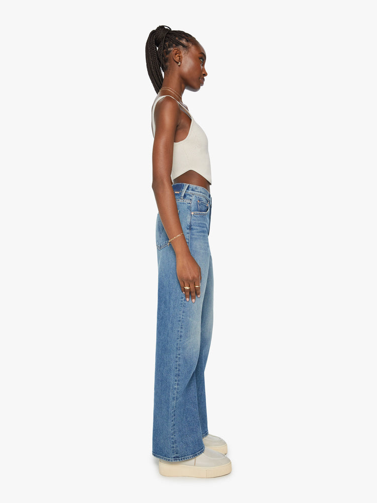 Side view of a woman super wide-leg jeans with a high rise and a long 32-inch inseam in a mid blue wash.