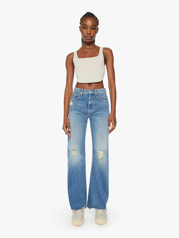 Front view of a woman super wide-leg jeans with a high rise and a long 32-inch inseam with a chewed hem in a mid-blue wash.