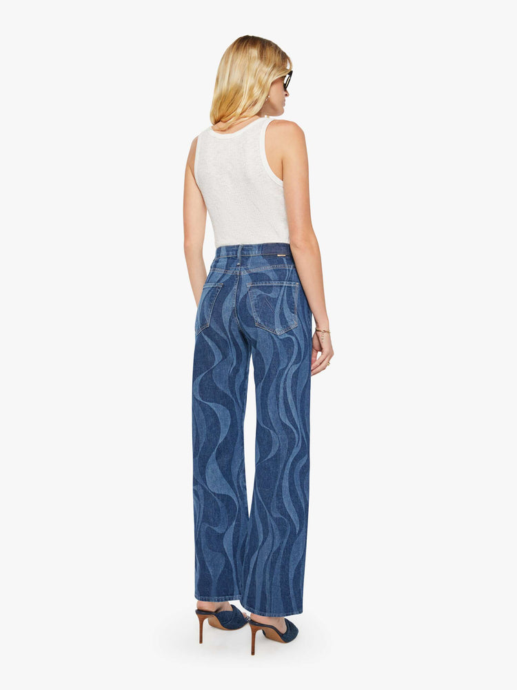 Back view of a woman in a dark blue with a laser-printed abstract stripe pattern wide-leg pants with a zip fly, high rise and a 32-inch inseam with a clean hem. 