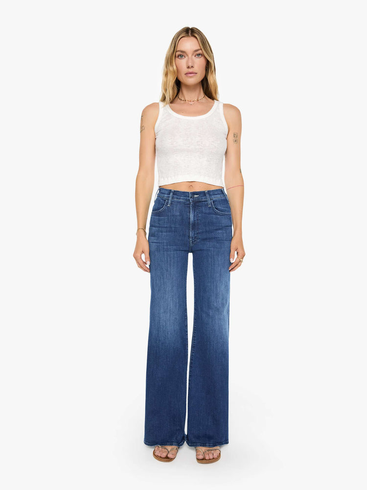 Front view of a woman wearing dark blue high rise jeans featuring a long inseam and wide leg.
