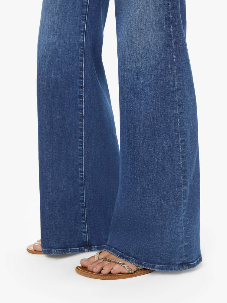 Close up view of a woman wearing dark blue high rise jeans featuring a long inseam and wide leg.