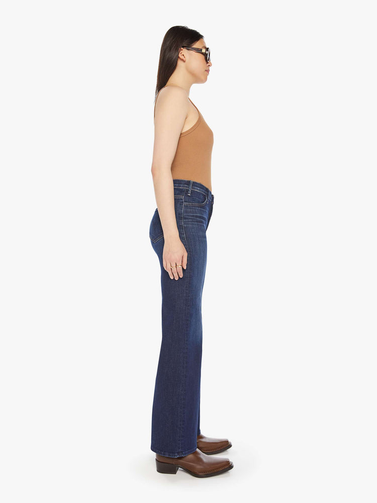 Side view of a woman dark blue wide leg jeans with a high rise, 32-inch inseam and a clean hem.