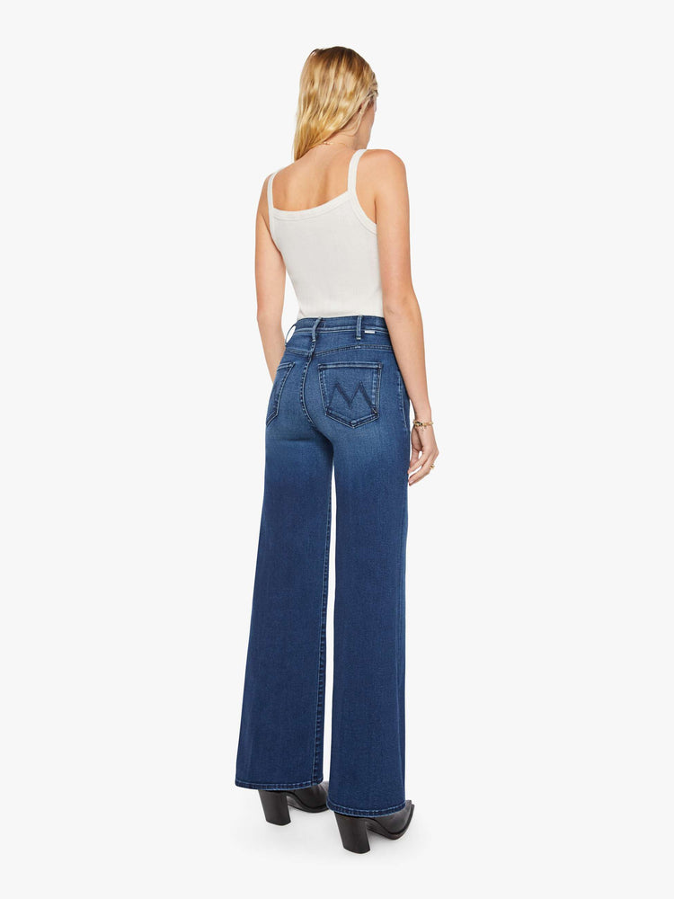 Back view of a woman in a dark blue wide leg jean with a high rise, 32-inch inseam and a clean hem.