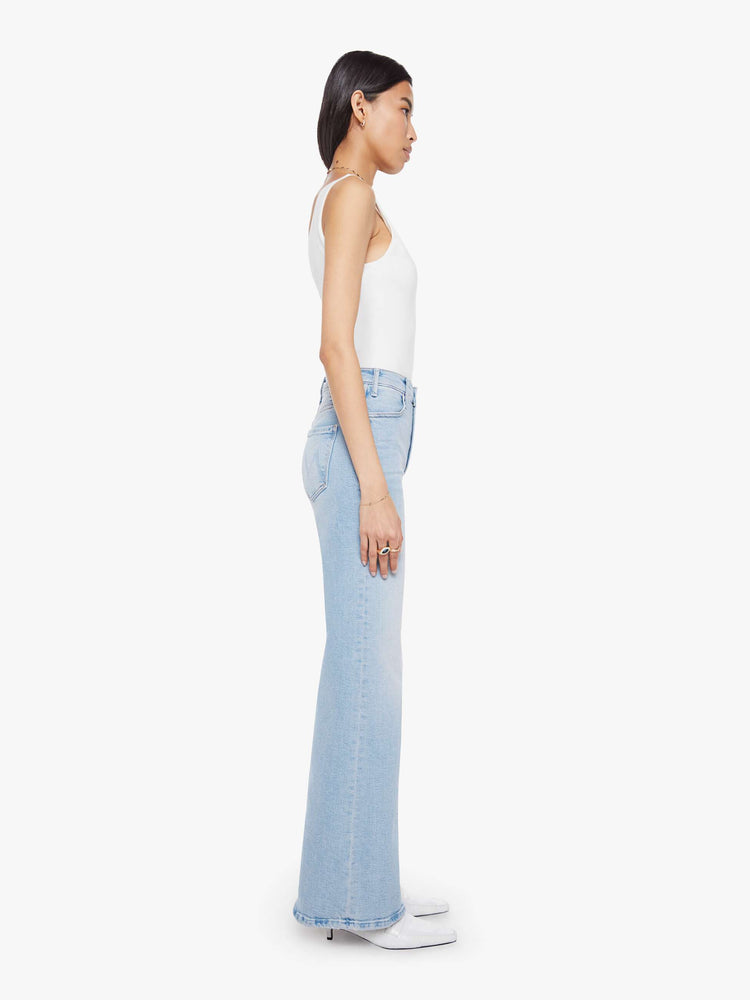 Side view of a woman in a light blue wide leg jeans with a high rise, zip fly, 32-inch inseam and a clean hem.