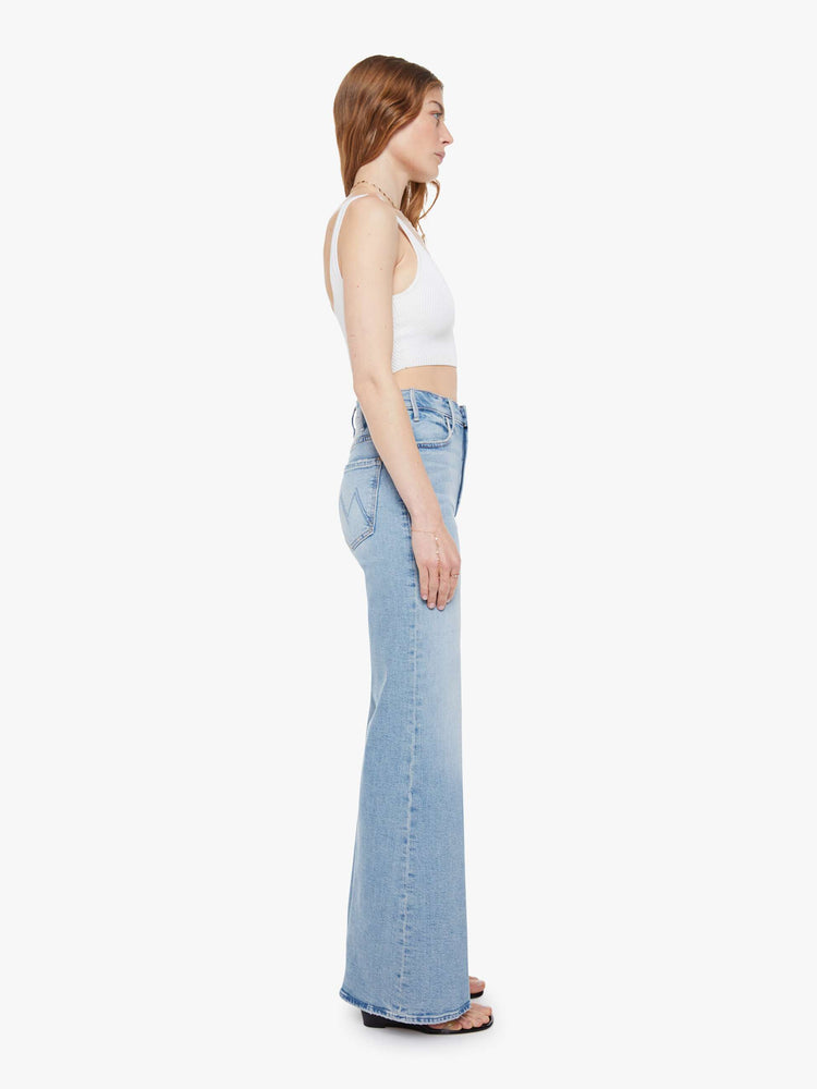 Side view of a woman in a light blue wide leg jeans with a high rise, zip fly, 32-inch inseam and a clean hem.