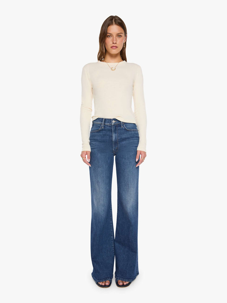 Front view of a woman in a mid blue wide leg jeans with a high rise, 33 7/8 inch inseam and a clean hem. 