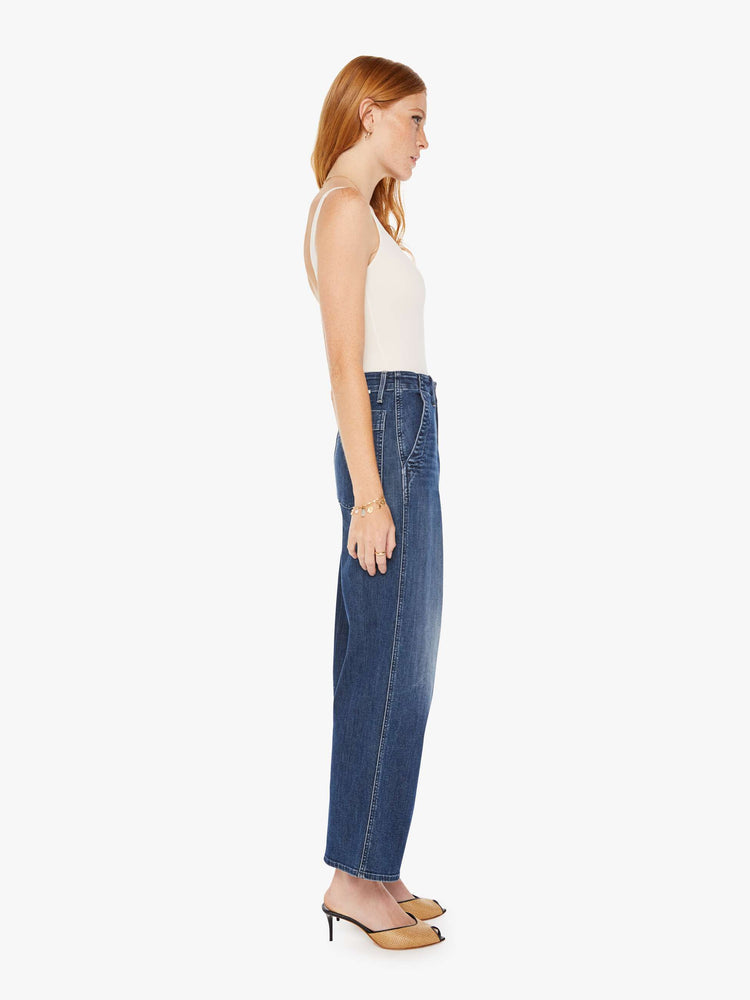 Side view of a womens dark blue denim jean featuring a super high rise and wide leg.
