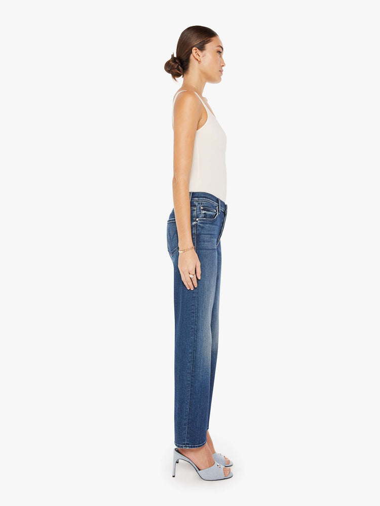 Side view of a dark blue wash jean featuring a high rise, straight leg, and a clean flood length hem.