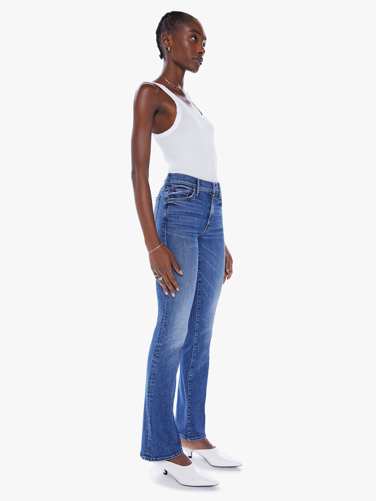 Side angle view of a woman flare jean with a mid-rise and a long 32-inch inseam with a clean hem in mid-blue wash.
