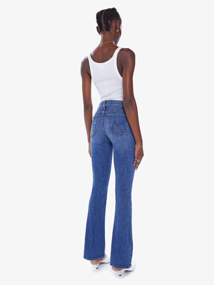 Back view of a woman flare jean with a mid-rise and a long 32-inch inseam with a clean hem in mid-blue wash.