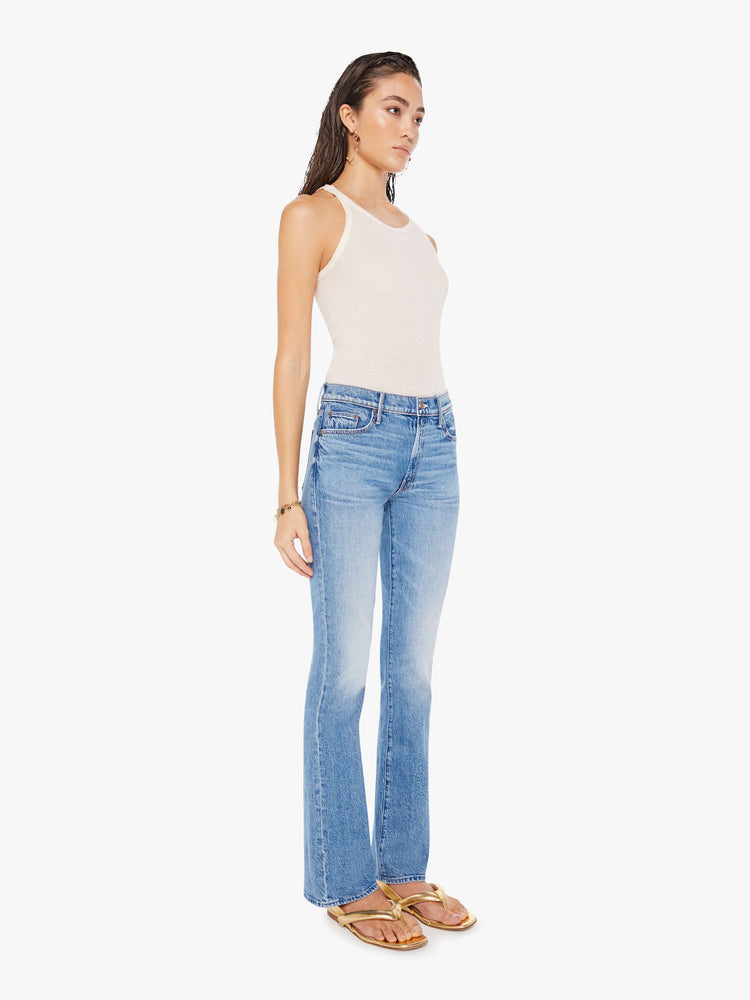 Front full body view of a woman wearing a medium blue wash jean featuring a mid rise and a full length flare inseam.