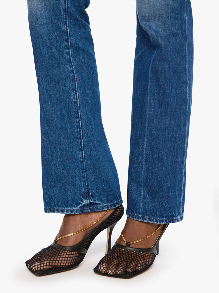 Hem view of a woman in blue bootcut jeans with a mid rise, zip fly and a long 32-inch inseam with a clean hem.